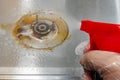 A man spraying chemical liquid to a gas stove at kitchen horizontal composition