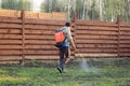 Man sprays grass with herbicide of a knapsack sprayer