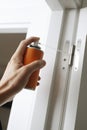 man sprays some lubricating oil on the hinge of a door