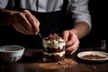 man spreading chocolate shavings over fresh tiramisu mousse