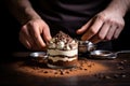 man spreading chocolate shavings over fresh tiramisu mousse