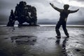 Man spreading his arms towards Hvitserkur rock in Iceland in the rain