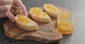 Man spreading orange marmalade on ciabatta slices on wood board