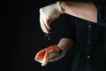 Man sprinkle salt on salmon meat on dark background