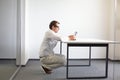 Man squatting at the desk, working with tablet