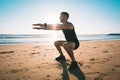 Man squatting or exercising on the beach during sunset. Sports and health Royalty Free Stock Photo