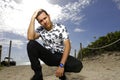 Man squatting on the sand with hand on head Royalty Free Stock Photo