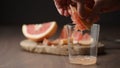 man squeeze grapefruit into tumbler glass on wood table Royalty Free Stock Photo