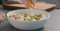 Man squeeze orange lemon into salad with kale, avocado, mozzarella and tomatoes in white bowl on kitchen countertop