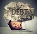 Man squeezed between laptop and rock. Student loan debt concept