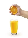 Hand squeezing orange into glass with drink of orange colour on the white background