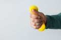 Man squeezing antistress ball on light background, closeup. Space for text