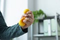 Man squeezing antistress ball in office, closeup