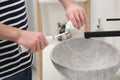 Man squeezing toothpaste from tube onto electric toothbrush above sink in bathroom, closeup Royalty Free Stock Photo