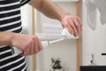 Man squeezing toothpaste from tube onto electric toothbrush in bathroom, closeup Royalty Free Stock Photo