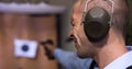 Man squinting eye, aiming with pistol at target in shooting range Royalty Free Stock Photo