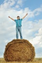 Man on a stack of straw against a field