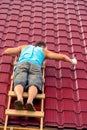 A man on the stairs with a hammer repairs the roof covering