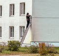 A man on the stairs installs a CCTV camera on the wall of the house Royalty Free Stock Photo