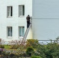 A man on the stairs installs a CCTV camera on the wall of the house Royalty Free Stock Photo