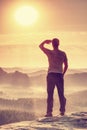 Man is stand on edge and enjoying dramatic overlook of misty landscape Royalty Free Stock Photo