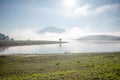 The man stand by lake anh Alone tree on the lake, sunrise at the mountai, foggy, cloud on the sky Royalty Free Stock Photo