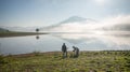 The man stand by lake anh Alone tree on the lake, sunrise at the mountai, foggy, cloud on the sky