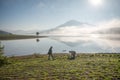 The man stand by lake anh Alone tree on the lake, sunrise at the mountai, foggy, cloud on the sky