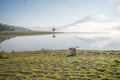 The man stand by lake anh Alone tree on the lake, sunrise at the mountai, foggy, cloud on the sky Royalty Free Stock Photo