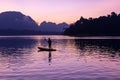 Man stand paddling on his kayak at Ratchaprapa dam, or known as Cheow Lan dam, at sunrise Royalty Free Stock Photo