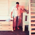 Man stand in room interior with furniture design. Sexy macho in shirt and jeans fashion. Guy do laundry housework in