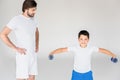 man standing akimbo and looking at son with dumbbells exercising Royalty Free Stock Photo