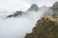 Man standing alone on mountain cliff edge foggy nature travel active healthy lifestyle Royalty Free Stock Photo