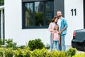 Man standing with attractive wife and cute kid near new house