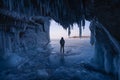 A man standing on Baikal frozen lake in front of ice cave, winter season in Siberia, Russia