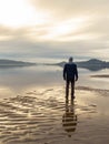 Man standing at the beach, reflections of the man in the water. Calm sea, mist and fog. Hamresanden, Kristiansand