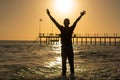 Man standing on the beach, raising his hands above his head at t Royalty Free Stock Photo