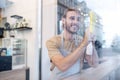 Man standing behind glass in cafe wiping surface Royalty Free Stock Photo