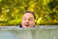 Man standing behind a round concrete wall, looking who is coming