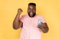 Man standing with cell phone in hands and clenching fist, celebrating his victory, looks at camera. Royalty Free Stock Photo