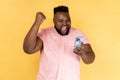 Man standing with cell phone in hands and clenching fist, celebrating his victory, looks at screen. Royalty Free Stock Photo