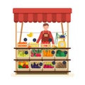 Man standing at counter of greengrocer`s shop or marketplace and selling fruits and vegetables. Male seller at place for