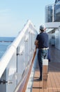 A man standing on the deck of a cruise ship and looking at the shore on a Sunny day, vertical shot Royalty Free Stock Photo