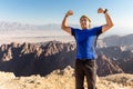 Man standing desert mountain summit posing strong hands victory. Royalty Free Stock Photo