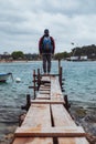 man standing at edge of the small fishing pier looking at stormy sea Royalty Free Stock Photo