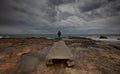 Man standing at the edge of a wooden pier in the stormy sea at sunset. Feeling free. Waves splashing on rocky coast Royalty Free Stock Photo