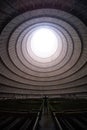 Man standing in an empty hall with a round window on the ceiling