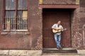 Man standing on factory loading dock playing acoustic guitar