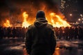 Man standing in front of a burning building in the middle of the city, Back view Aggressive man without face in hood against