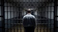 Man standing in front of prison bars looking down a dark hallway Royalty Free Stock Photo